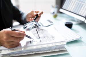 A man examines a document with a magnifying glass, carefully inspecting its contents.
